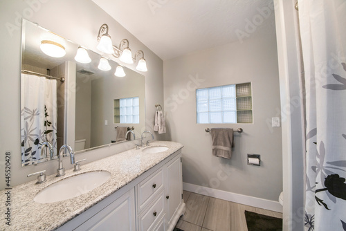 Interior of a bathroom with double vanity sink and a window with glass cube panel