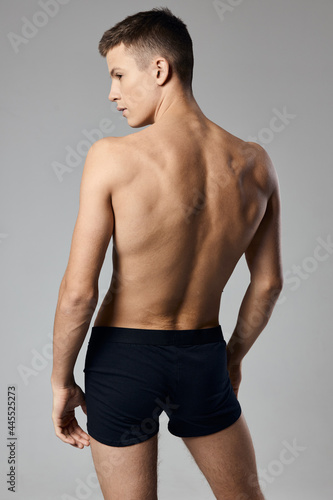  man with pumped up arm muscles naked back gray background model