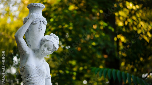 sculpture of a girl in the spring park. An old statue in a park of a sensual semi-nude Greek or Italian Renaissance woman with a vase in a city park. sunny day in the summer garden. close-up
