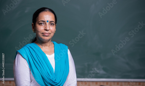 Portrait of a confident Woman teacher in front of Blackboard in Class room