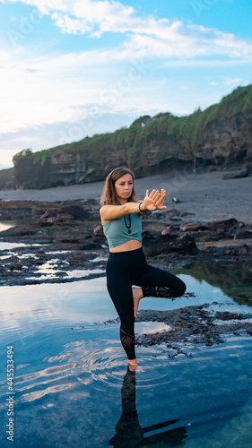 Girl doing yoga by the sea while standing in the water..