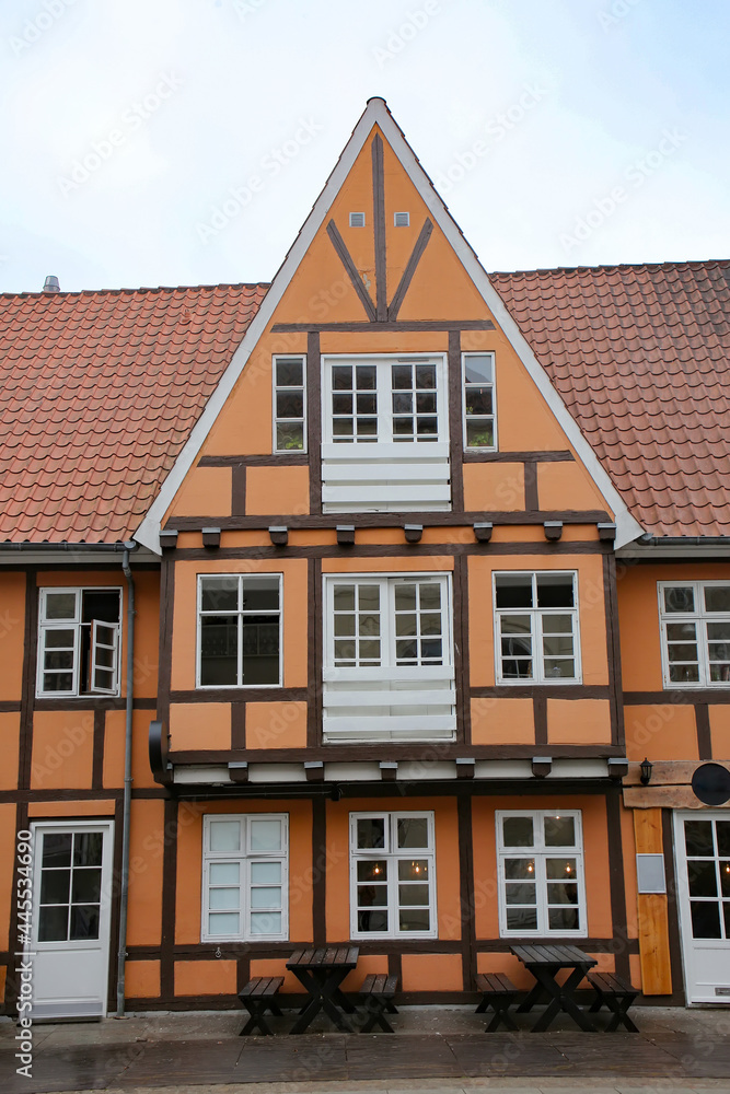 Historic and typical orange and wooden painted timbered building with white windows and doors in the city center, Aalborg, Denmark. Historic and typical orange and wooden painted timbered building with white windows and doors in the city center, Aalborg, Denmark.
