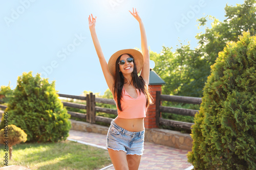 Happy young woman with sunglasses and hat outdoors
