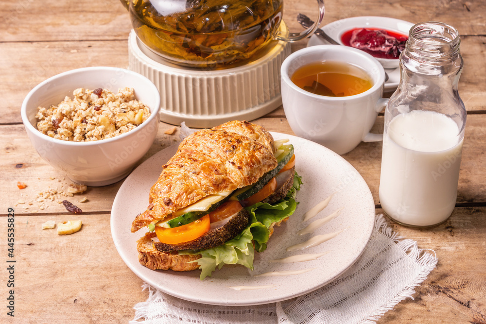 Healthy breakfast concept. Morning good mood with tea, croissant, granola, milk, and jam Healthy breakfast concept. Morning good mood with tea, croissant, granola, milk, and jam
