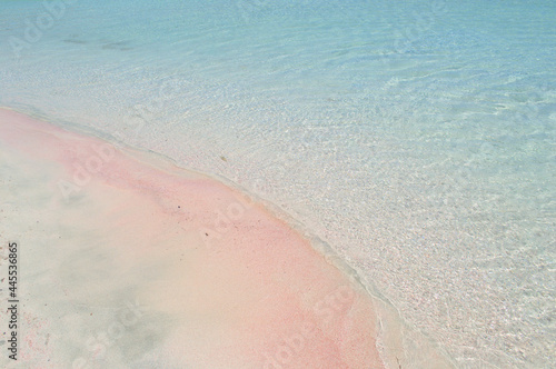 Pink paradise sandy beach with blue water.