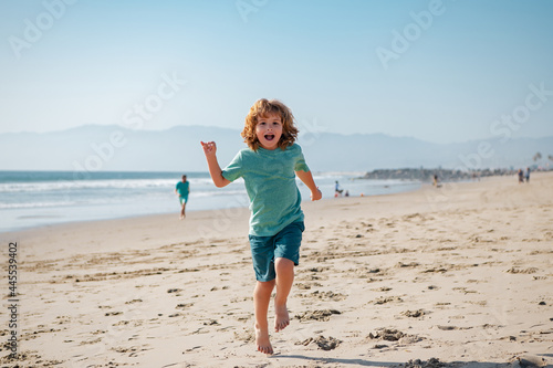 Kid boy running and jumping in summer sandy beach. © Volodymyr