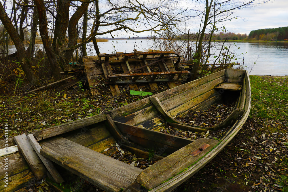 An old wooden wrecked boat on the shore of the lake in the fall.