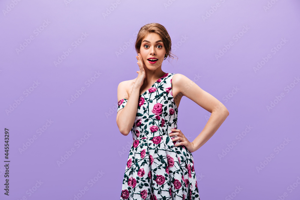 Woman in floral dress looking surprised on purple background. Modern wonderful lady in summer outfit posing into camera on isolated backdrop.. Woman in floral dress looking surprised on purple background. Modern wonderful lady in summer outfit posing into camera on isolated backdrop..