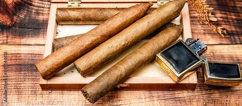 Cigars in box and vintage lighter. Cuban cigars wooden background. Cigar smoking. Cigar tobacco photo