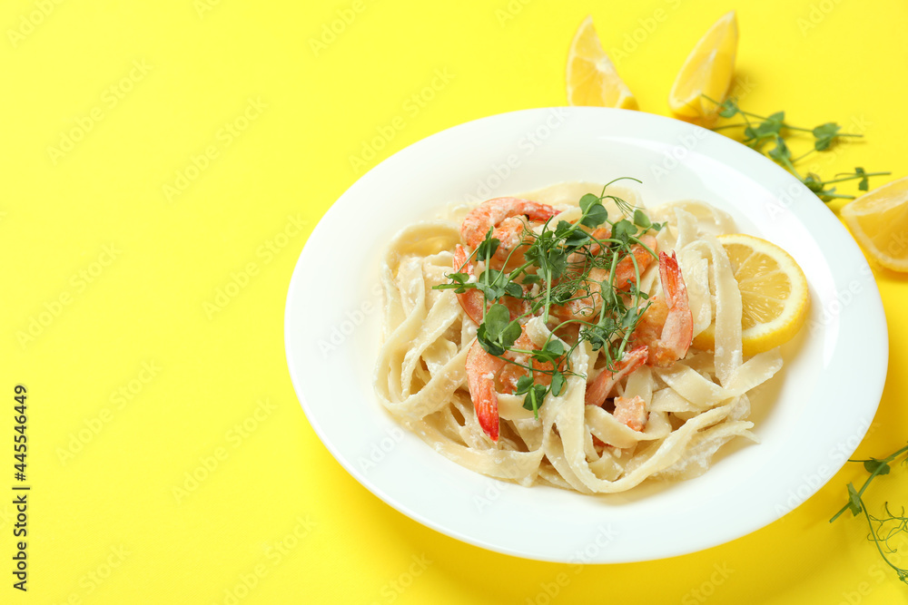 Plate of tasty shrimp pasta on yellow background
