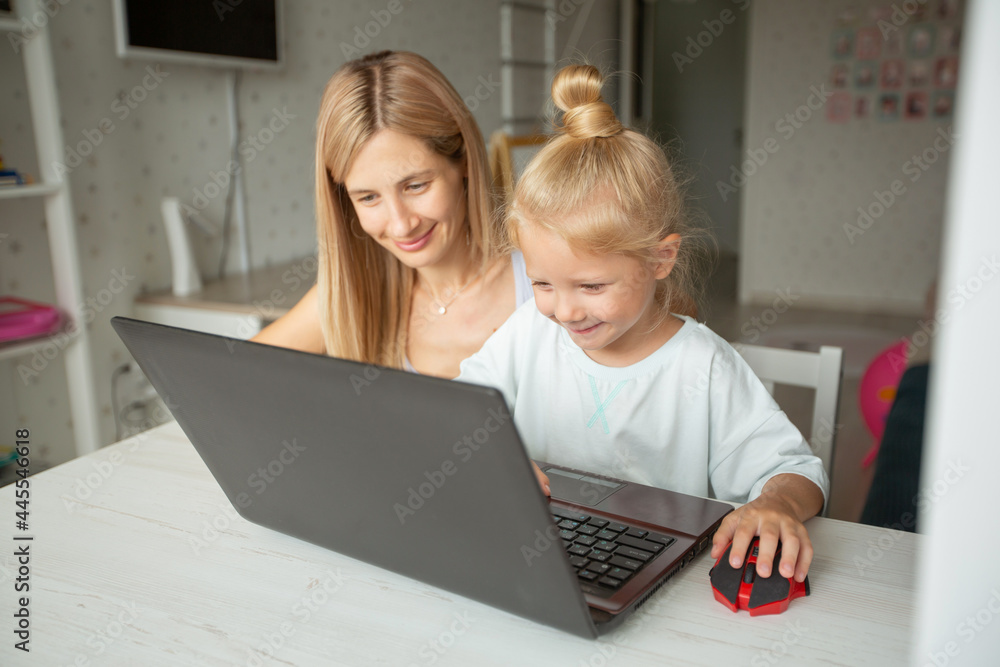 beautiful mother with daughter are sitting at home with laptop beautiful mother with daughter are sitting at home with laptop