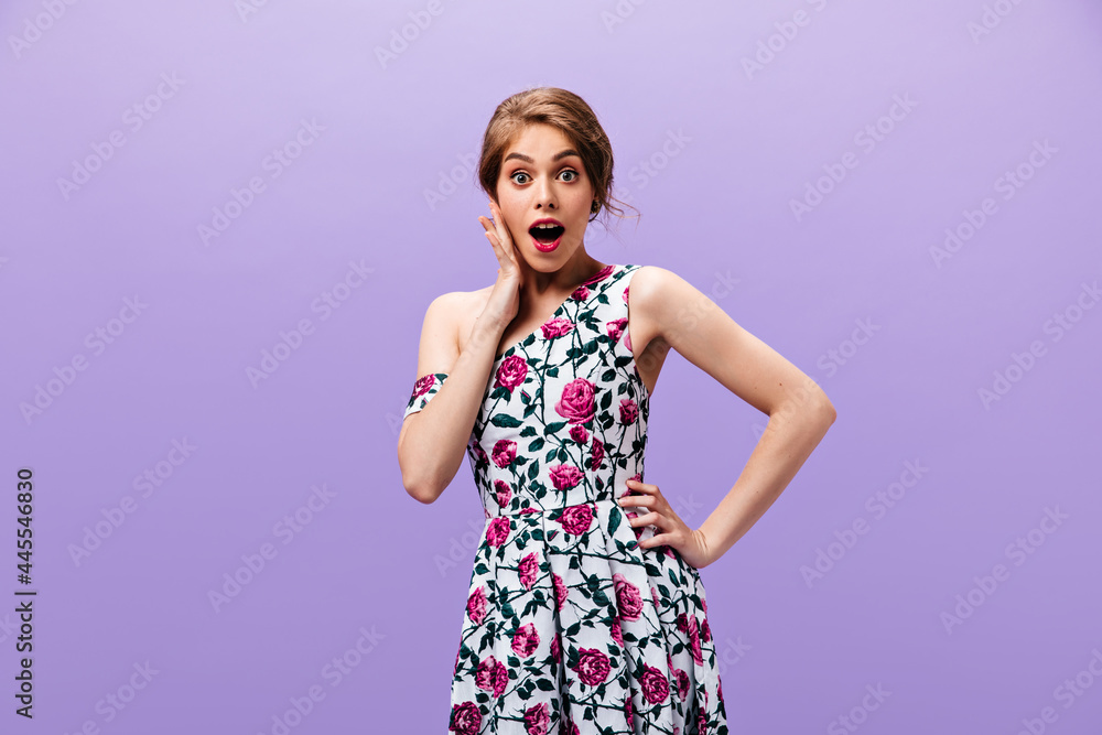 Shocked lady in floral dress poses on isolated background. Surprised young woman with red lips in stylish clothes looking into camera.. Shocked lady in floral dress poses on isolated background. Surprised young woman with red lips in stylish clothes looking into camera..