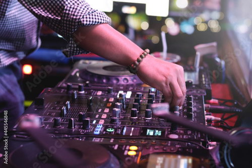 DJ hand playing live set and mixing music on controller turntable console mixing desk at stage in the night club, music beach party festiva and nightlife