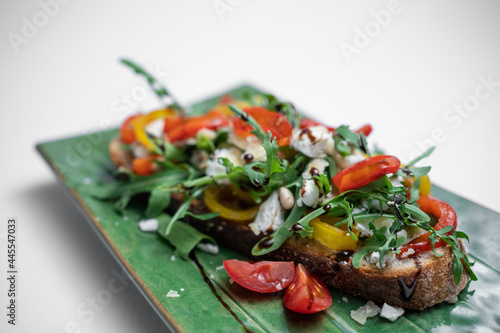 bruschetta or toast bread with arugula, tomatoes and cheese on white background