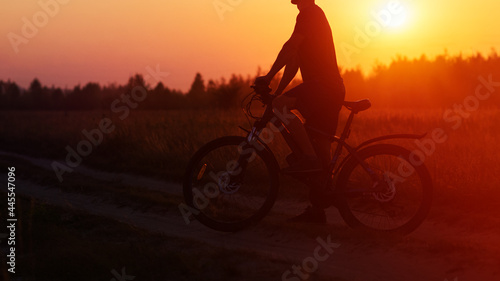 The silhouette of a cyclist at sunset in a field. Cycling on a summer evening copy space