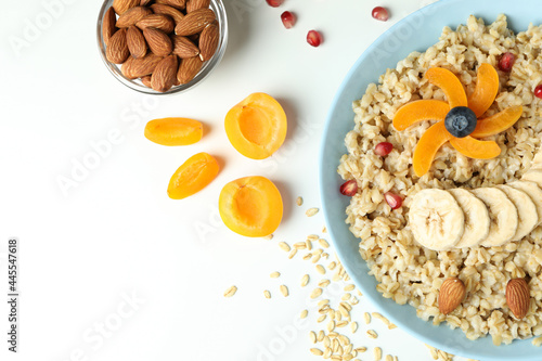 Bowl of oatmeal and ingredients on white background