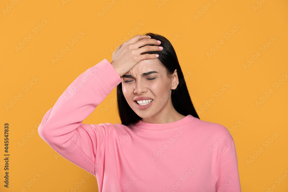 Woman suffering from migraine on yellow background Woman suffering from migraine on yellow background