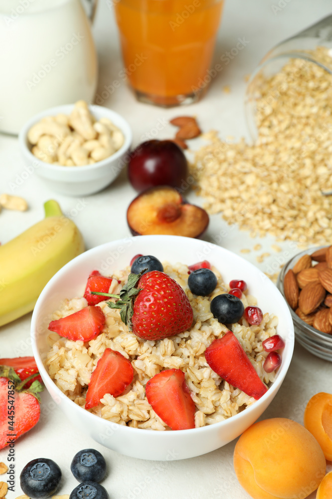 Bowl of oatmeal and ingredients for cooking on white background Bowl of oatmeal and ingredients for cooking on white background