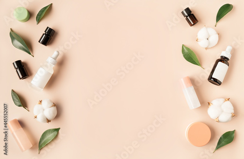 Beautiful spa composition of natural cosmetics mockup bottles with cotton flowers and green leaves on pastel background. Top view. Flat lay style. Copy space.