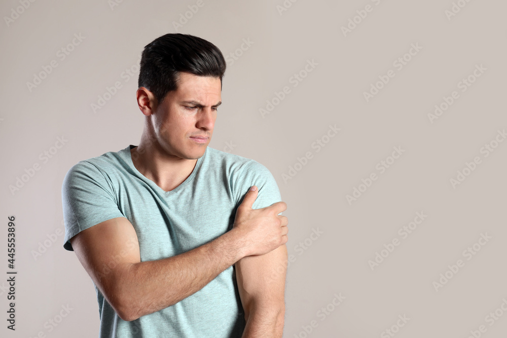 Man suffering from shoulder pain on beige background. Space for text Man suffering from shoulder pain on beige background. Space for text