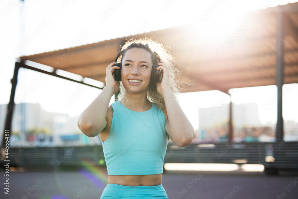 Young sporty woman with headphones. Beautiful woman listening the music while preparing for the training