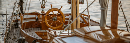 A close-up of instruments and wooden wheel of nautical vessel. Sailboat at sea background