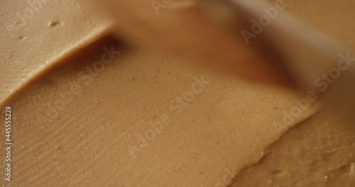 Peanut Butter Spreading with a Knife Creating Creamy Caramel Color Background a Macro Shot 
