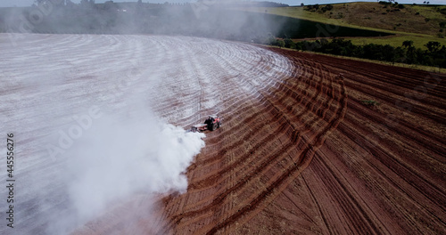 Tractor applying limestone to the soil to correct acidity photo