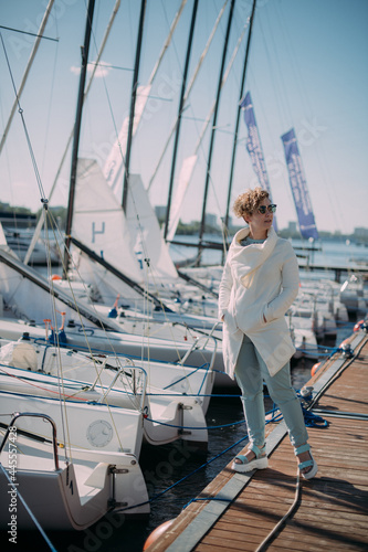 Young woman at the pier with sailing yachts. A beautiful girl walks near the moored sport yachts