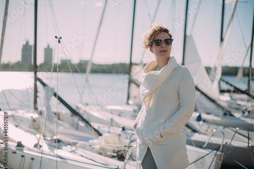 Young woman at the pier with sailing yachts. A beautiful girl walks near the moored sport yachts © Anna