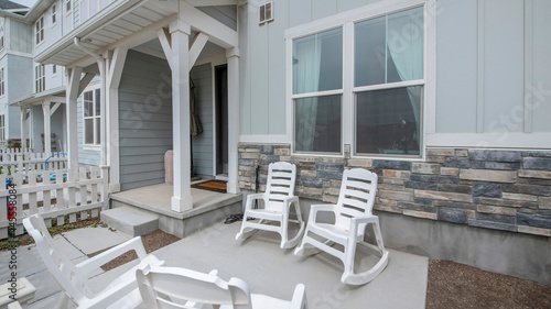 Pano Patio in front of a townhouse with wooden white fence and rocking chairs photo