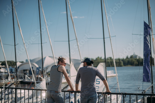 Young men, coaches of the yachting school at the marina with sailing yachts. © Anna