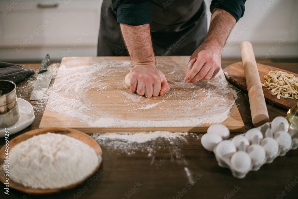 A male chef prepares noodles at home in the kitchen.