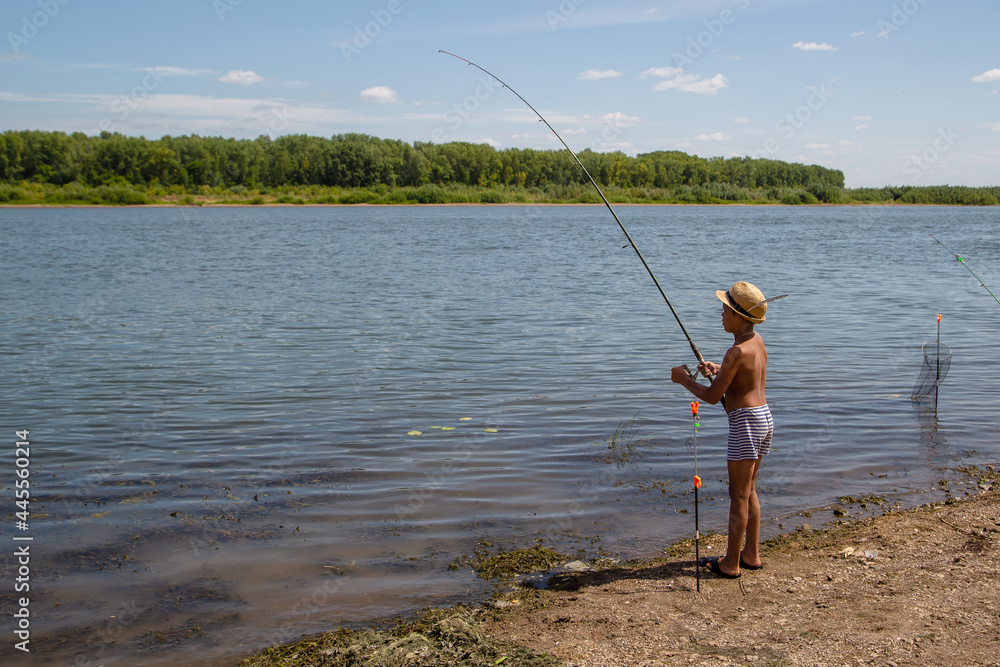 Little fisherman in a hat, pulls out a fish, on a hot summer day Little fisherman in a hat, pulls out a fish, on a hot summer day