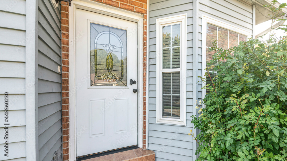 Fototapeta premium Pano Front door exterior with bricks and vinyl siding wall