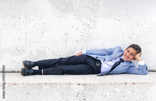 Schoolboy laughing, lying on the concrete floor