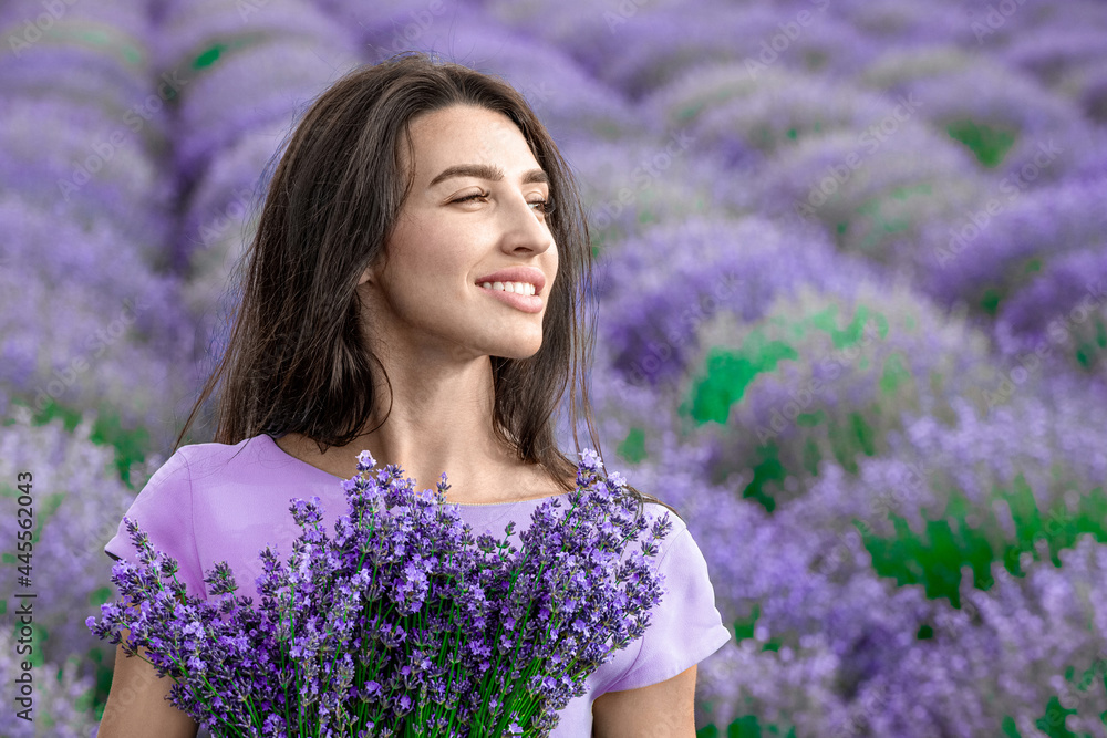 Lovely young woman wearing purple dress and posing in purple lavender field closeup; professional retouch. Lovely young woman wearing purple dress and posing in purple lavender field closeup; professional retouch.