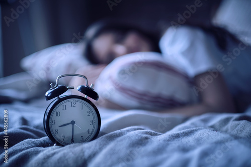 Tableau sur toile Young lady resting in her bed, midnight time shown on alarm clock, night dreams
