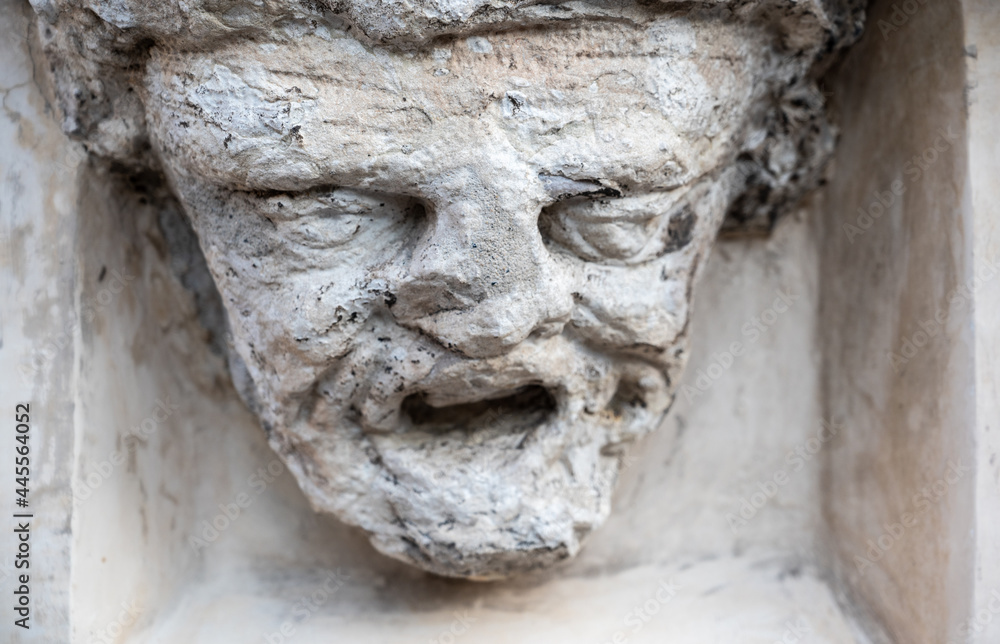 Trento, Italy, June 2021. Ancient bas-relief of a face in stone on the facade of a house. Time has deteriorated the features of the face making it difficult to recognize.