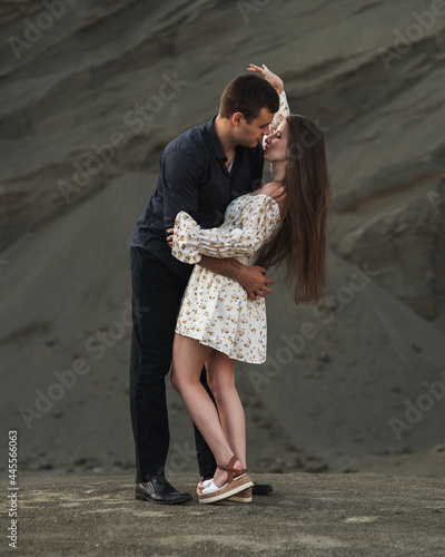 Happy couple dancing outdoors at summertime on gray sand background