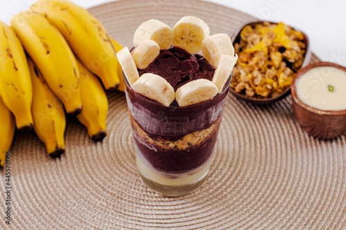 Brazilian açaí glass with ingredients and bananas in the background