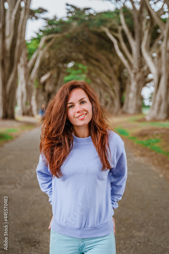 Fototapeta Naklejka Na Ścianę i Meble -  Inspiring portrait of a young woman with long hair in the atmospheric Cypress Tree Tunnel near San Francisco, USA