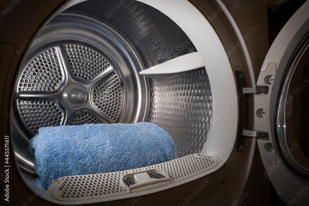 Blue towels are stacked in the tumble dryer. Laundry. Clean concept