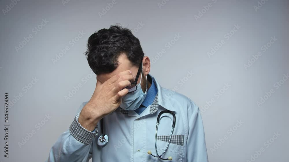 Stress of healthcare workers during COVID-19. Worried and tired arab doctor, suffering from headache, slow motion Stress of healthcare workers during COVID-19. Worried and tired arab doctor, suffering from headache, slow motion