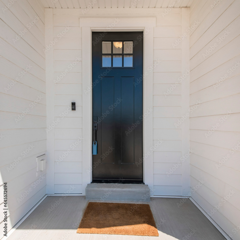 Fototapeta premium Square frame Exterior of a house with a view of black wooden door with glass panel and an enginered wood sidings
