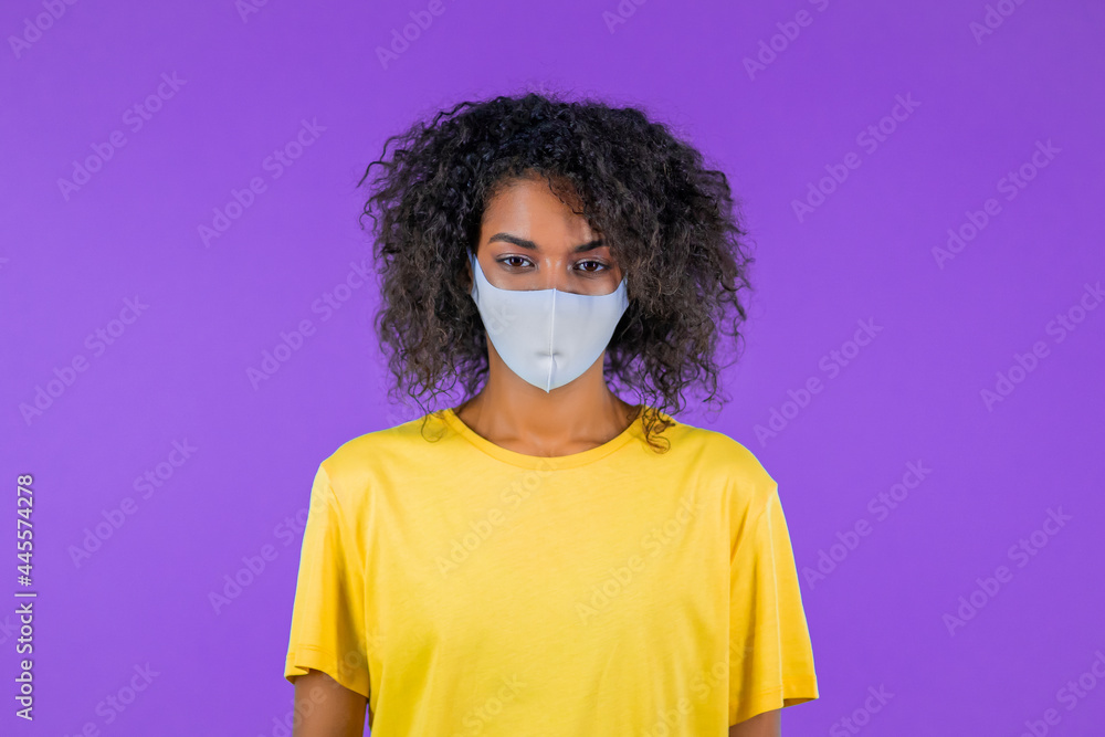 African woman in facial medical protective mask, quarantine concept. Purple studio background. African woman in facial medical protective mask, quarantine concept. Purple studio background.