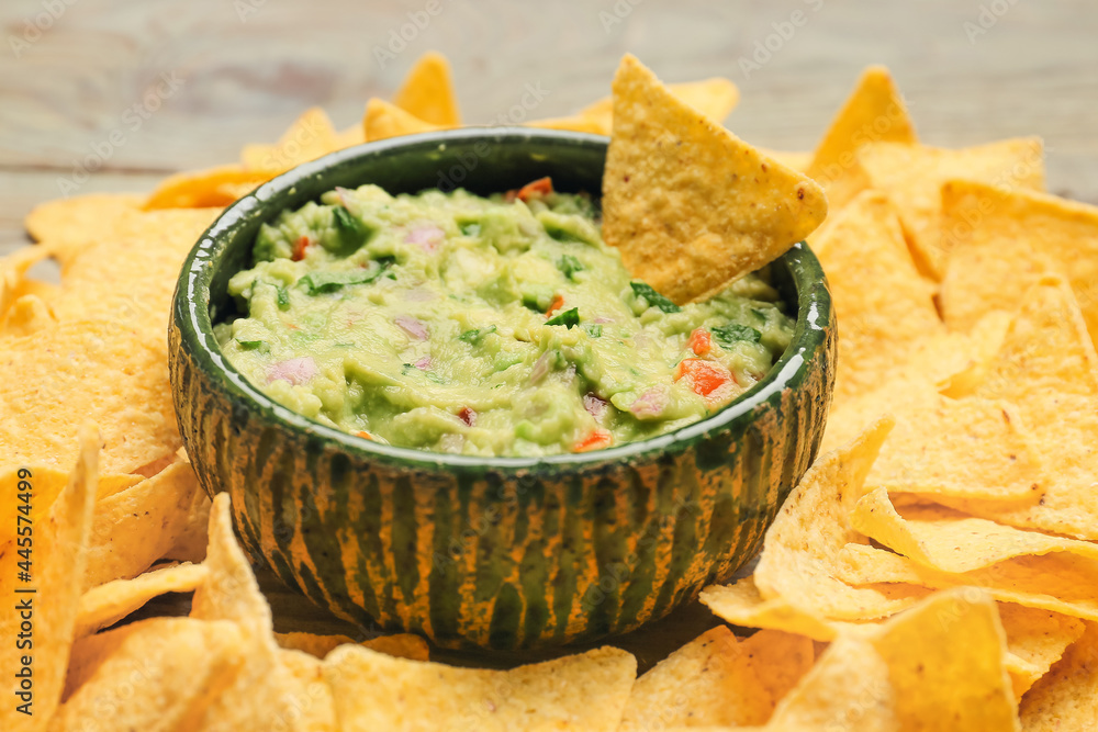 Bowl with tasty guacamole and nachos on table, closeup Bowl with tasty guacamole and nachos on table, closeup