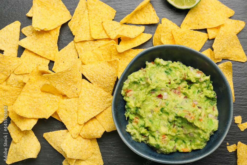 Bowl with tasty guacamole and nachos on dark background Bowl with tasty guacamole and nachos on dark background