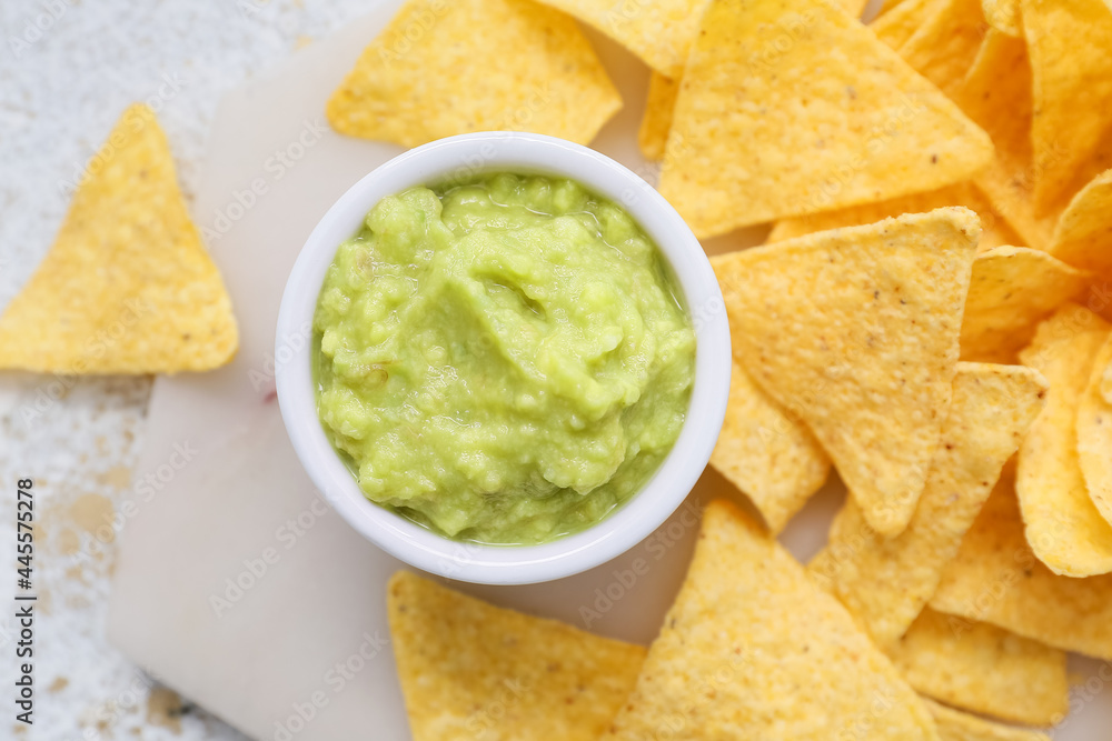 Bowl with tasty guacamole and nachos on light background, closeup Bowl with tasty guacamole and nachos on light background, closeup