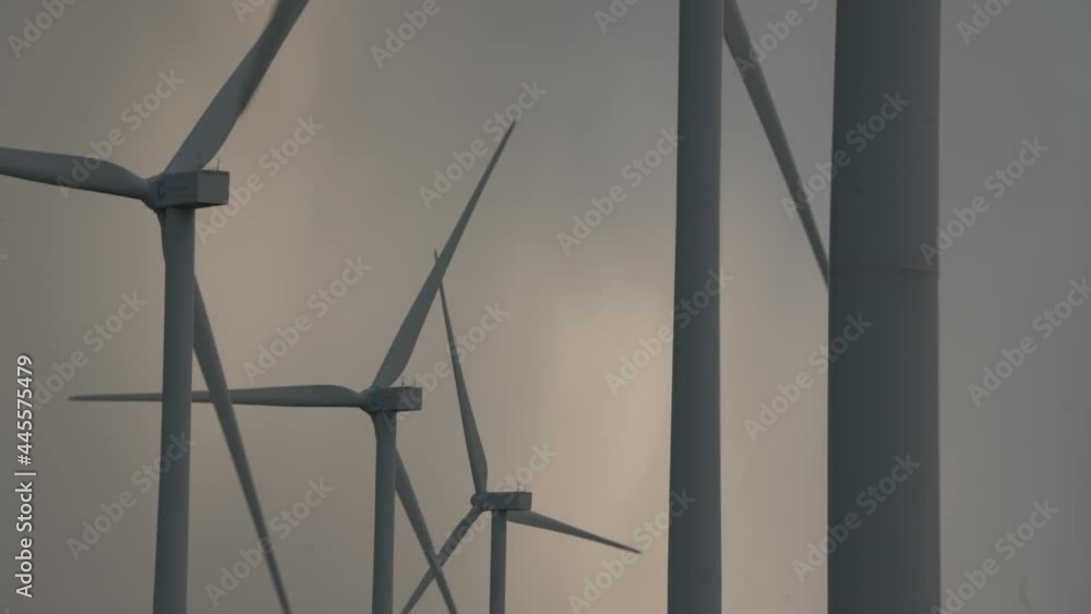 Windmill silhouettes with blades rotating in grey sky with dense clouds on wind field in evening before hurricane. Sustainable clean energy concept. Windmill silhouettes with blades rotating in grey sky with dense clouds on wind field in evening before hurricane. Sustainable clean energy concept.